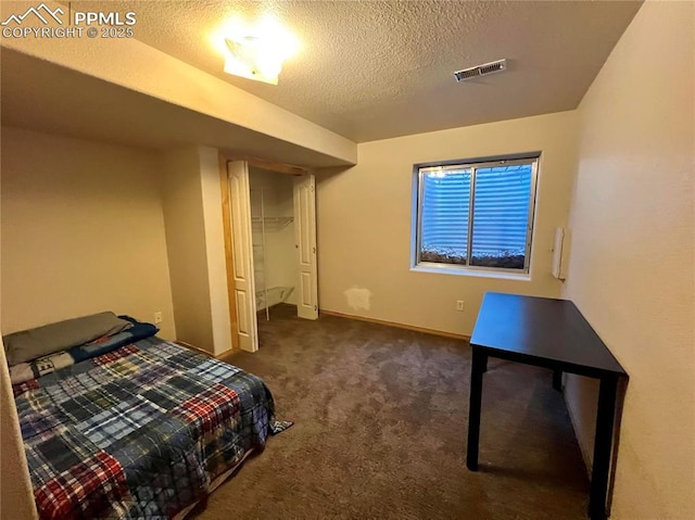 bedroom with a closet, visible vents, carpet flooring, a textured ceiling, and baseboards