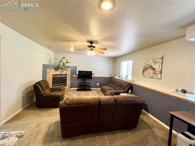 carpeted living area featuring a textured ceiling, ceiling fan, a fireplace, visible vents, and baseboards