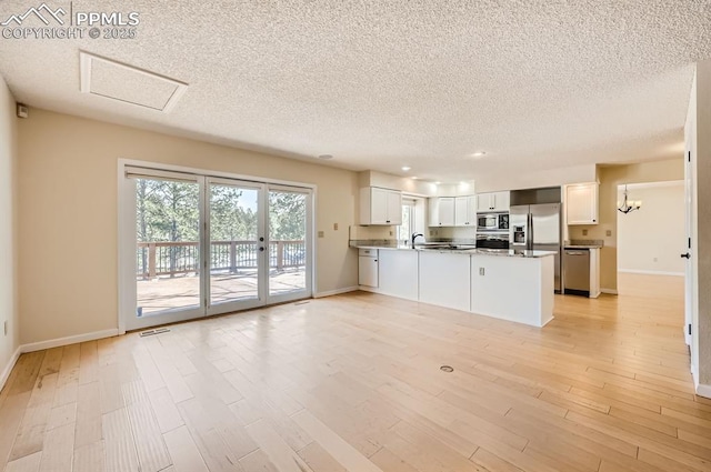 unfurnished living room featuring light wood-type flooring, baseboards, visible vents, and a sink