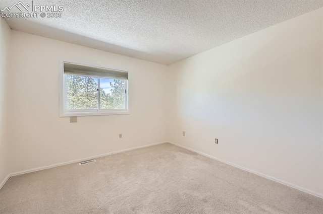 carpeted spare room featuring a textured ceiling, visible vents, and baseboards