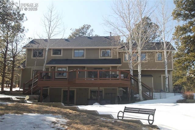 snow covered house featuring stairway and a deck