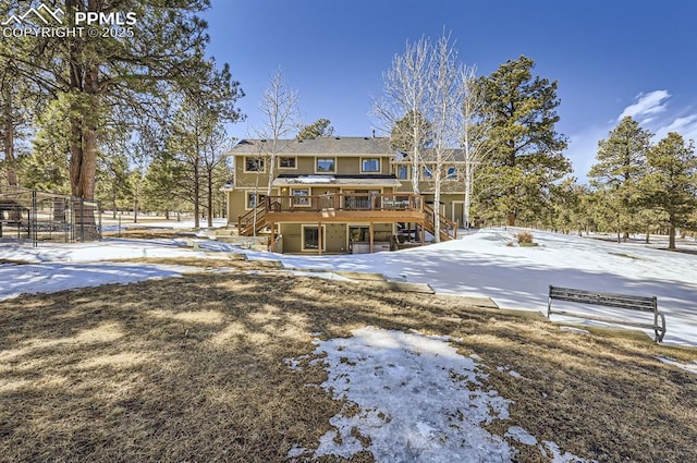 snow covered house featuring stairway and a wooden deck