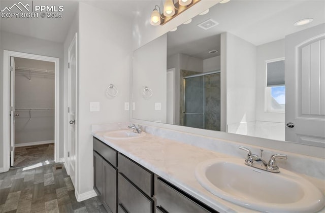 bathroom featuring a walk in closet, a sink, visible vents, and a shower stall