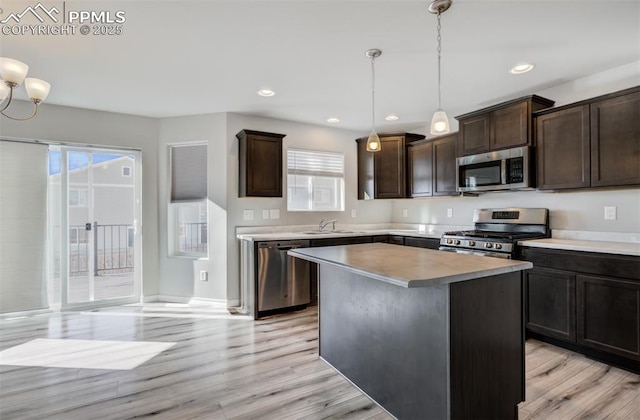 kitchen featuring appliances with stainless steel finishes, light wood-style floors, a sink, and dark brown cabinetry