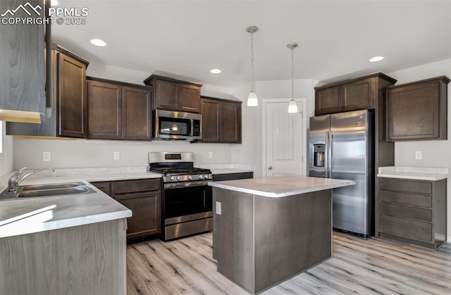 kitchen featuring light wood finished floors, stainless steel appliances, dark brown cabinets, light countertops, and a sink