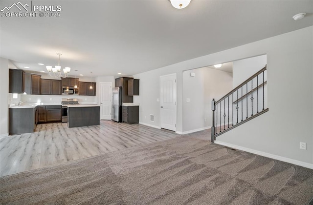 kitchen with open floor plan, stainless steel appliances, dark brown cabinets, and light countertops