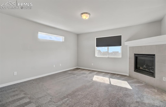 unfurnished living room with carpet, a fireplace, and baseboards