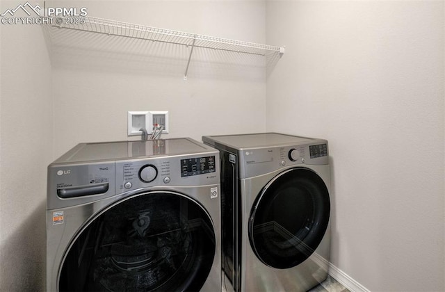 clothes washing area featuring laundry area, independent washer and dryer, and baseboards