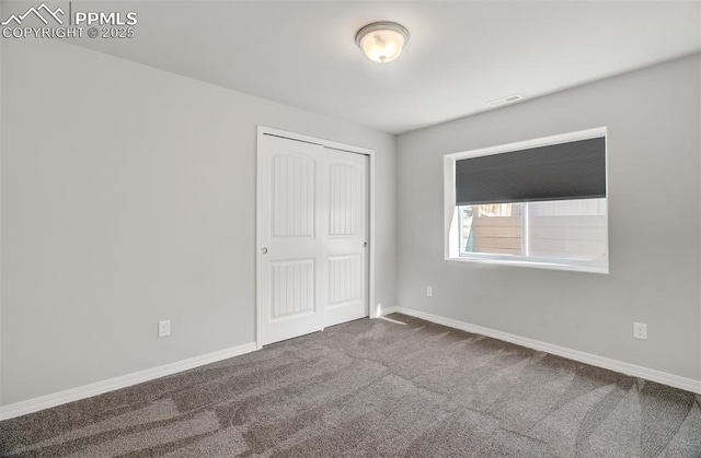 unfurnished bedroom with dark colored carpet, a closet, visible vents, and baseboards