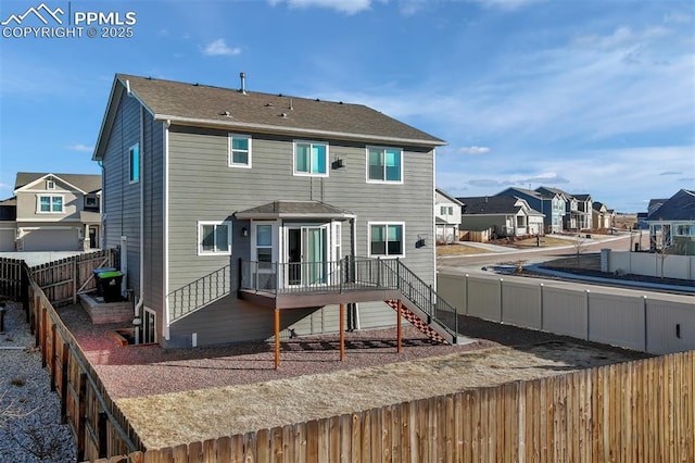 rear view of house featuring a fenced backyard, a residential view, stairway, and a wooden deck