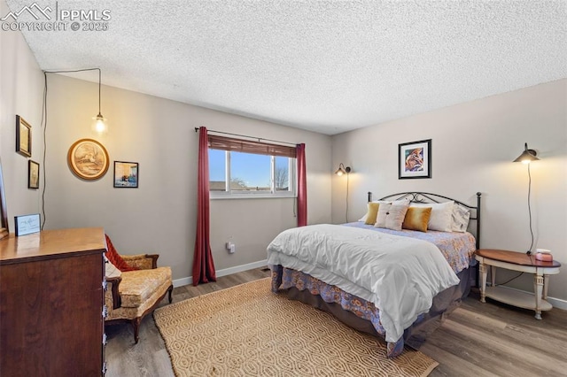 bedroom with a textured ceiling, baseboards, and wood finished floors