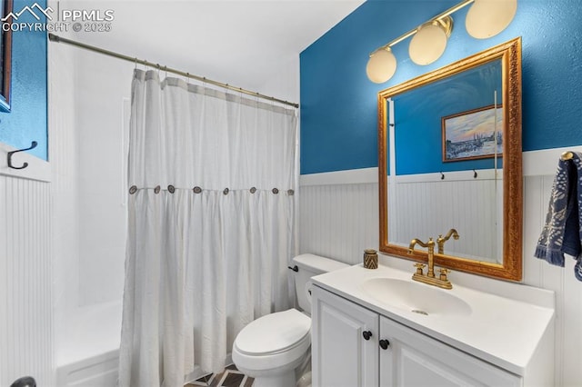 full bathroom with wainscoting, vanity, toilet, and shower / bath combo with shower curtain