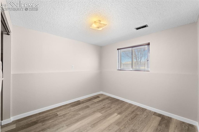 empty room featuring visible vents, baseboards, and wood finished floors