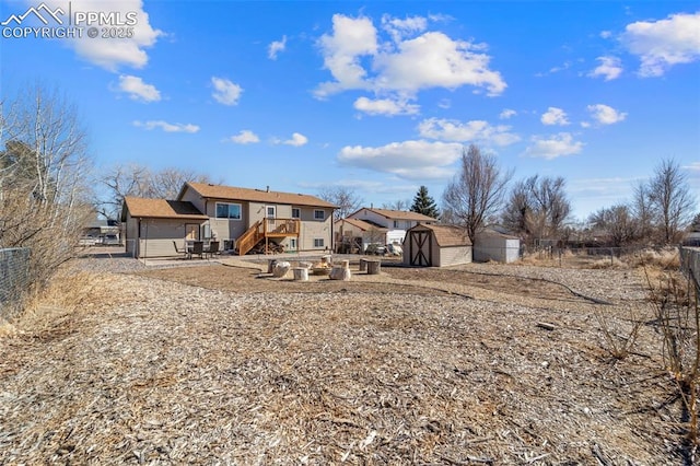 rear view of property featuring a shed, an outdoor structure, and fence