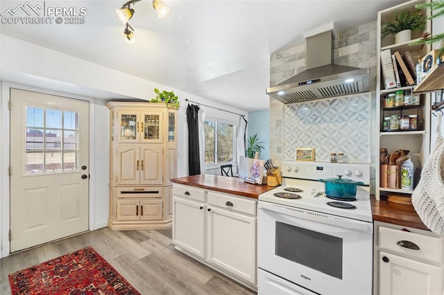 kitchen featuring white electric range oven, wall chimney exhaust hood, butcher block countertops, and light wood finished floors