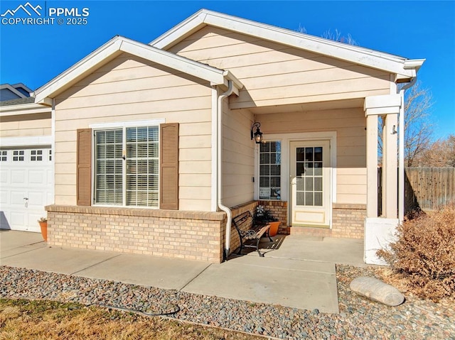 view of front of house featuring an attached garage, fence, and brick siding