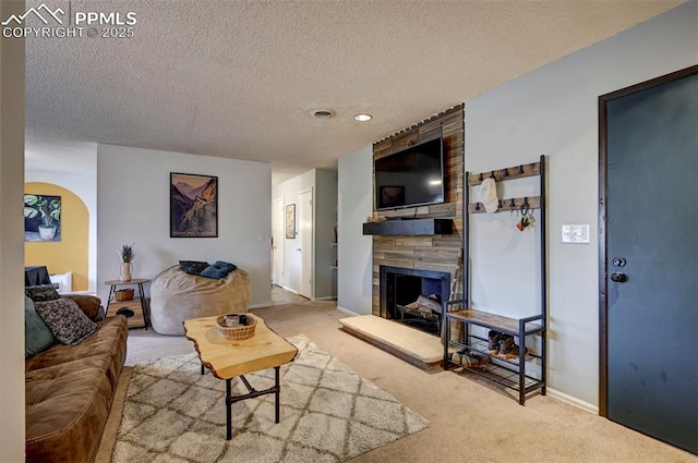 living area with carpet, visible vents, a fireplace, and a textured ceiling