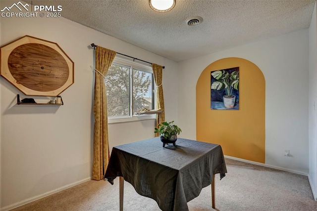 dining area featuring visible vents, arched walkways, baseboards, carpet, and a textured ceiling