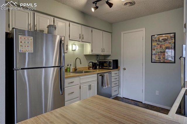 kitchen featuring visible vents, appliances with stainless steel finishes, light countertops, white cabinetry, and a sink