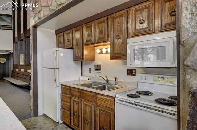 kitchen featuring light countertops, white appliances, brown cabinetry, and a sink