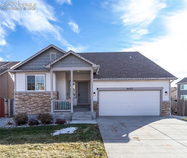 craftsman-style house with a shingled roof, an attached garage, fence, stone siding, and driveway