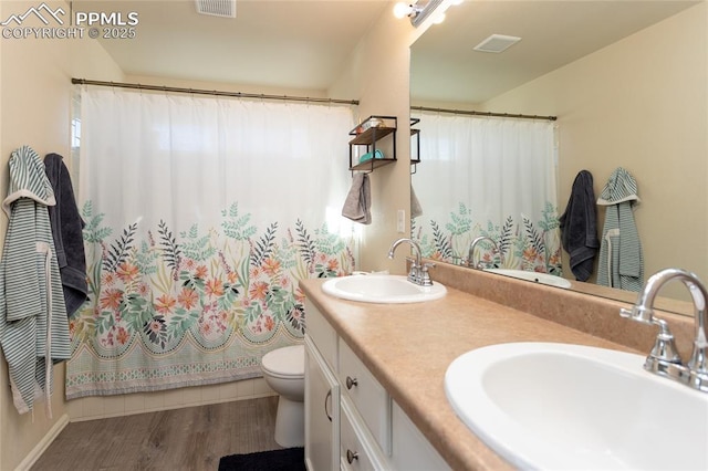 bathroom featuring visible vents, wood finished floors, a sink, and toilet