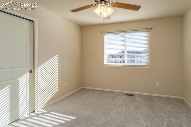 carpeted empty room featuring a ceiling fan, visible vents, and baseboards