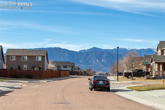 view of road featuring street lights, sidewalks, a mountain view, curbs, and a residential view