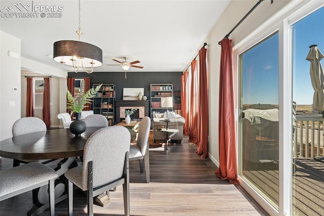 dining space featuring light wood-style flooring, baseboards, and ceiling fan with notable chandelier