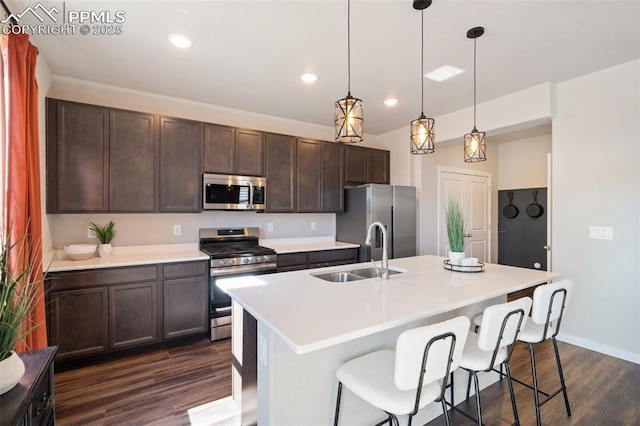 kitchen featuring appliances with stainless steel finishes, dark wood-style flooring, a sink, and dark brown cabinets