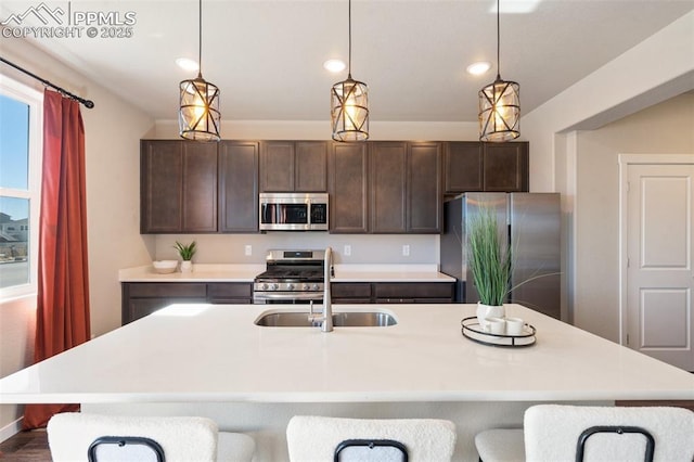 kitchen with stainless steel appliances, light countertops, a sink, and dark brown cabinets