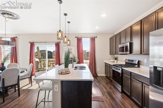 kitchen with stainless steel appliances, light countertops, a sink, and dark wood-type flooring