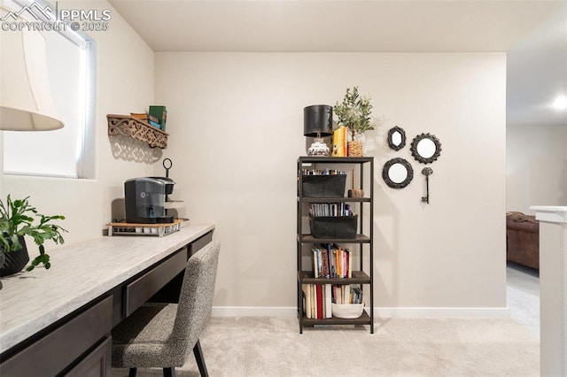 home office with light carpet, built in desk, and baseboards