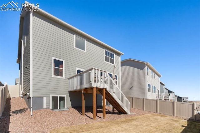 rear view of house with a fenced backyard, stairway, and a deck