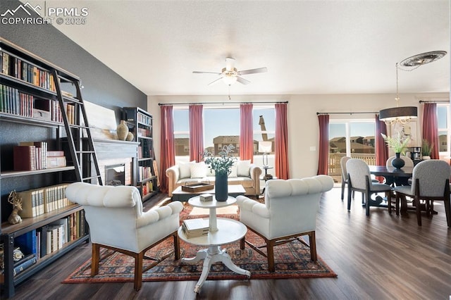 living area with a fireplace, wood finished floors, and a ceiling fan