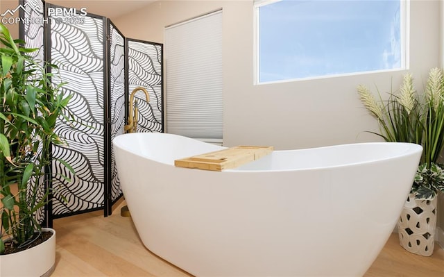 bathroom featuring a freestanding bath and wood finished floors