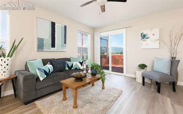 living area featuring ceiling fan, light wood-style flooring, and baseboards