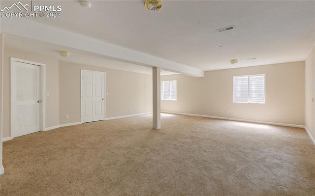 basement featuring carpet, plenty of natural light, visible vents, and baseboards