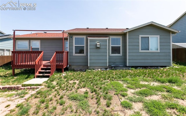 rear view of property featuring fence and a wooden deck