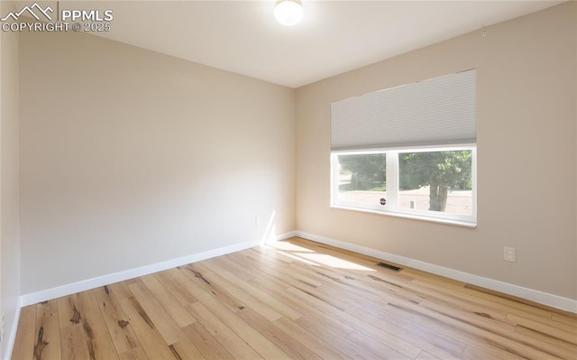 spare room with visible vents, baseboards, and wood finished floors