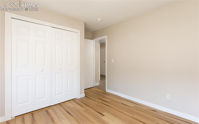 unfurnished bedroom featuring a closet, baseboards, and light wood finished floors