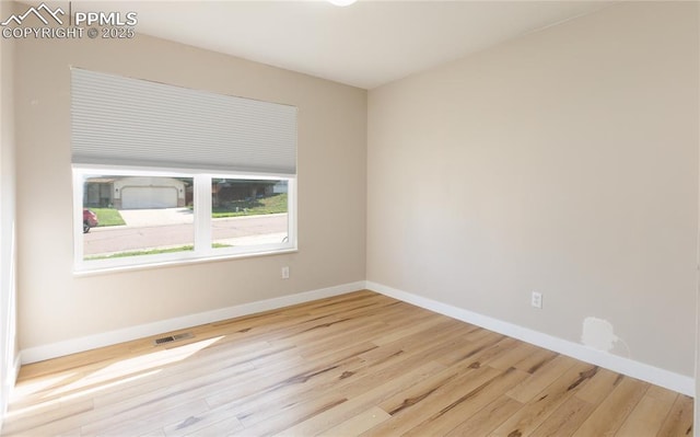 spare room featuring visible vents, baseboards, and wood finished floors