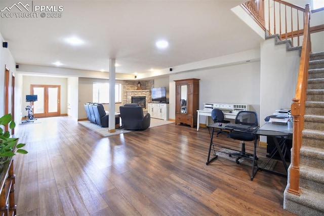 office space with french doors, a stone fireplace, wood finished floors, and baseboards