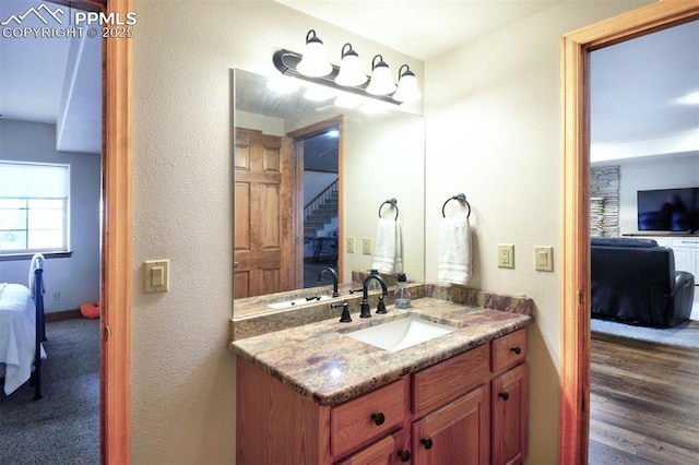 bathroom with a textured wall, wood finished floors, connected bathroom, and vanity