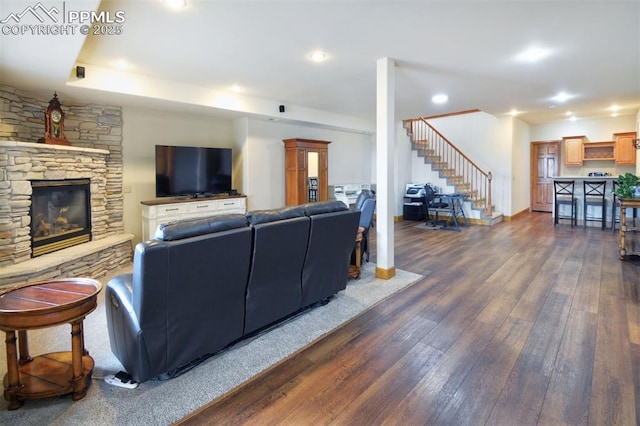 living room with a stone fireplace, stairway, dark wood finished floors, and recessed lighting