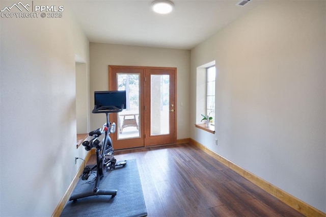 exercise area with visible vents, baseboards, and wood finished floors