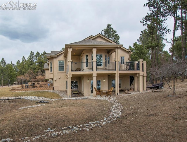 rear view of property with a patio, a balcony, and stucco siding