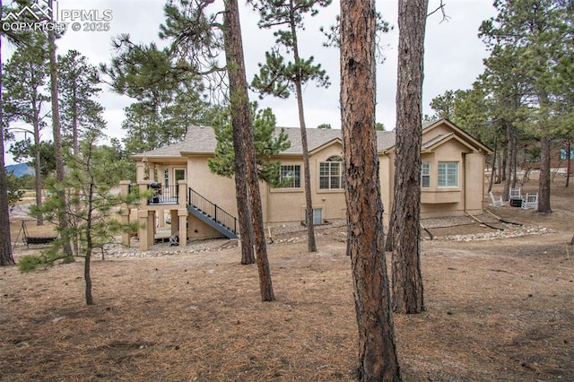 back of property featuring stairs and stucco siding