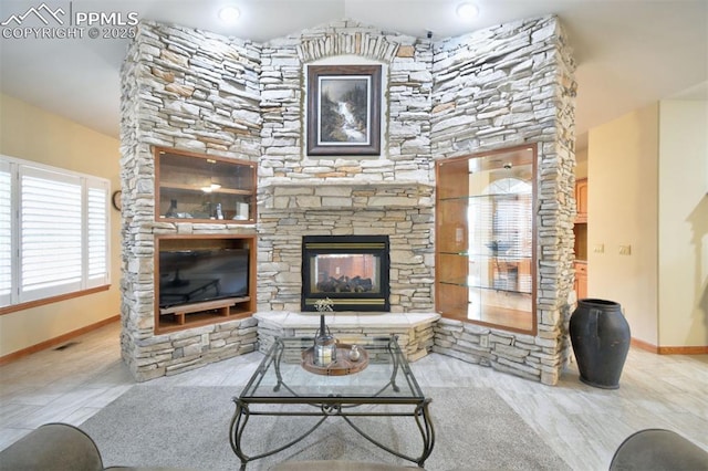 living area featuring lofted ceiling, visible vents, a stone fireplace, and baseboards