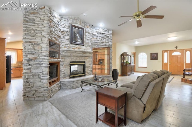 living area featuring a ceiling fan, a fireplace, and high vaulted ceiling